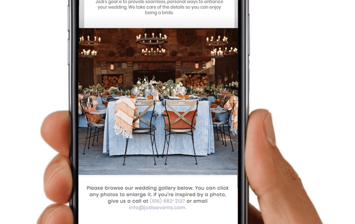 Hand holding a smartphone displaying a wedding planning website with a table setting image and contact information.