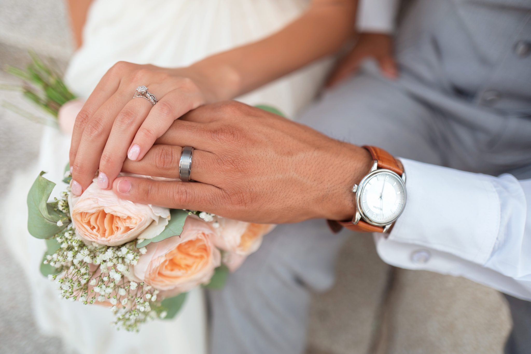 photo of wedding couple holding hands showing rings