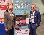 Two men standing next to a banner advertising web design and SEO services.